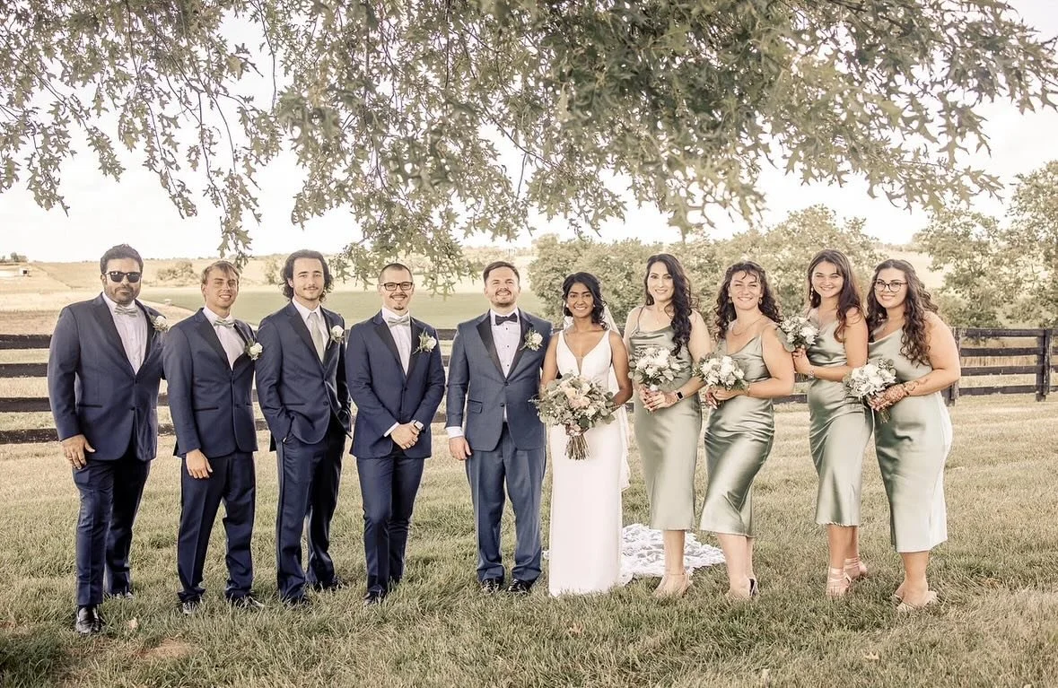 Bride, groom, and wedding party posing under a tree at The Show Barn